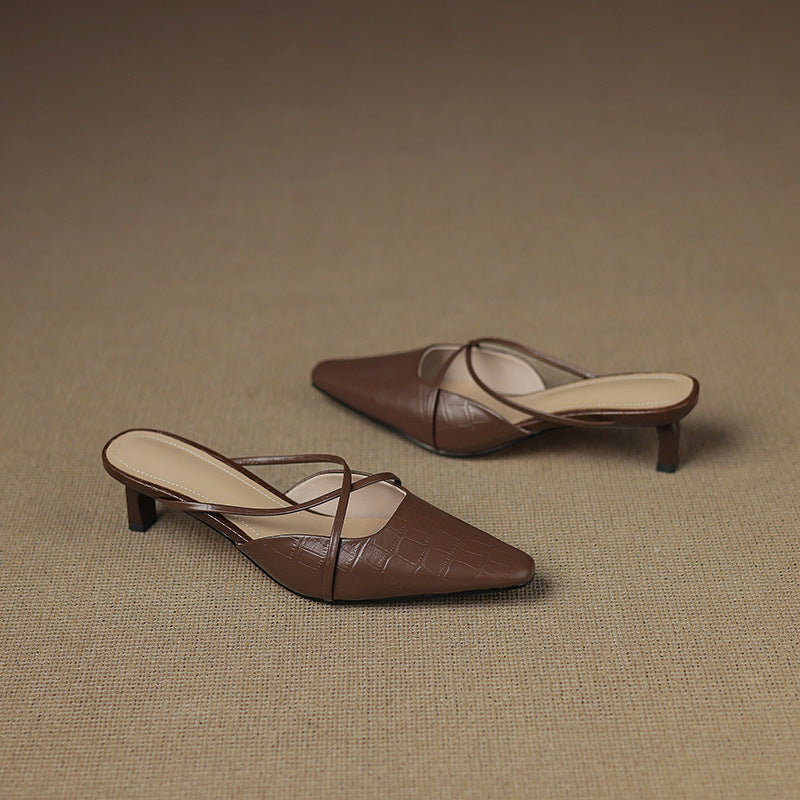 Brown genuine leather mules with crisscross straps and mid heel, pair on surface.