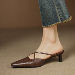 Brown genuine leather mules with open back, crisscross straps, and mid heel.