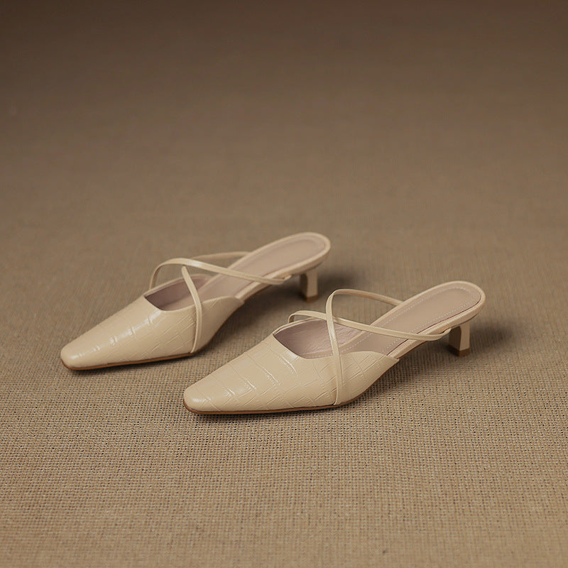 Two beige pointed-toe mules with crisscross straps and low block heel