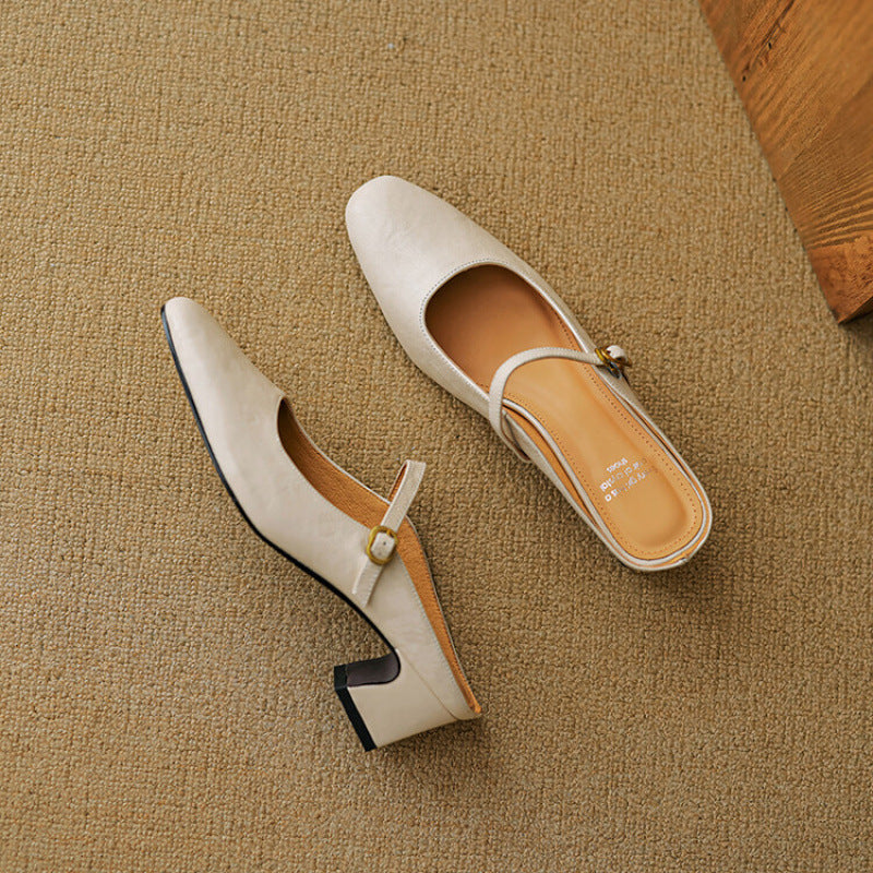 Pair of beige leather mules with low block heel and gold buckle strap.