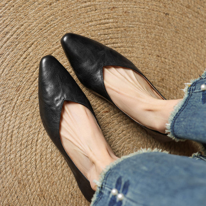 Black leather slip-on mules with pointed toe, V-cut vamp, and low heel.