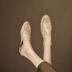 Beige leather mule viewed from side on bare feet, slip-on with low heel