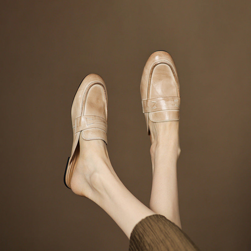Beige leather mule viewed from side on bare feet, slip-on with low heel