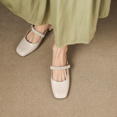 Beige leather Mary Jane mules with elastic strap and low block heel on feet