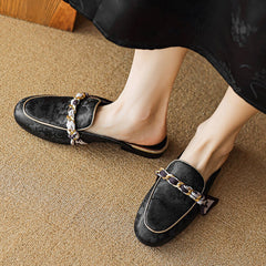 Black leather mules with rounded toe and gold-toned chain strap detail