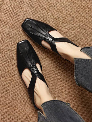 Black square-toe leather mules with knotted bow vamp, worn with jeans.