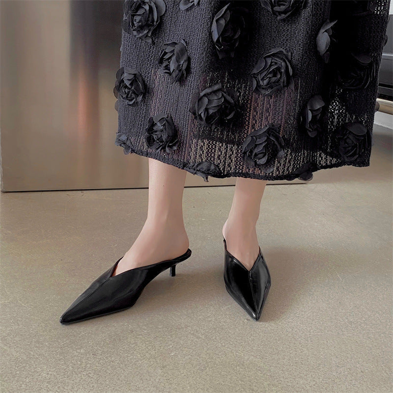 Black pointed-toe mules with low block heel, shown on feet
