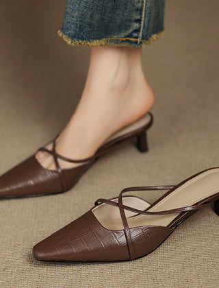 Brown genuine leather mules with crisscross straps and mid heel, worn with jeans cuffs.
