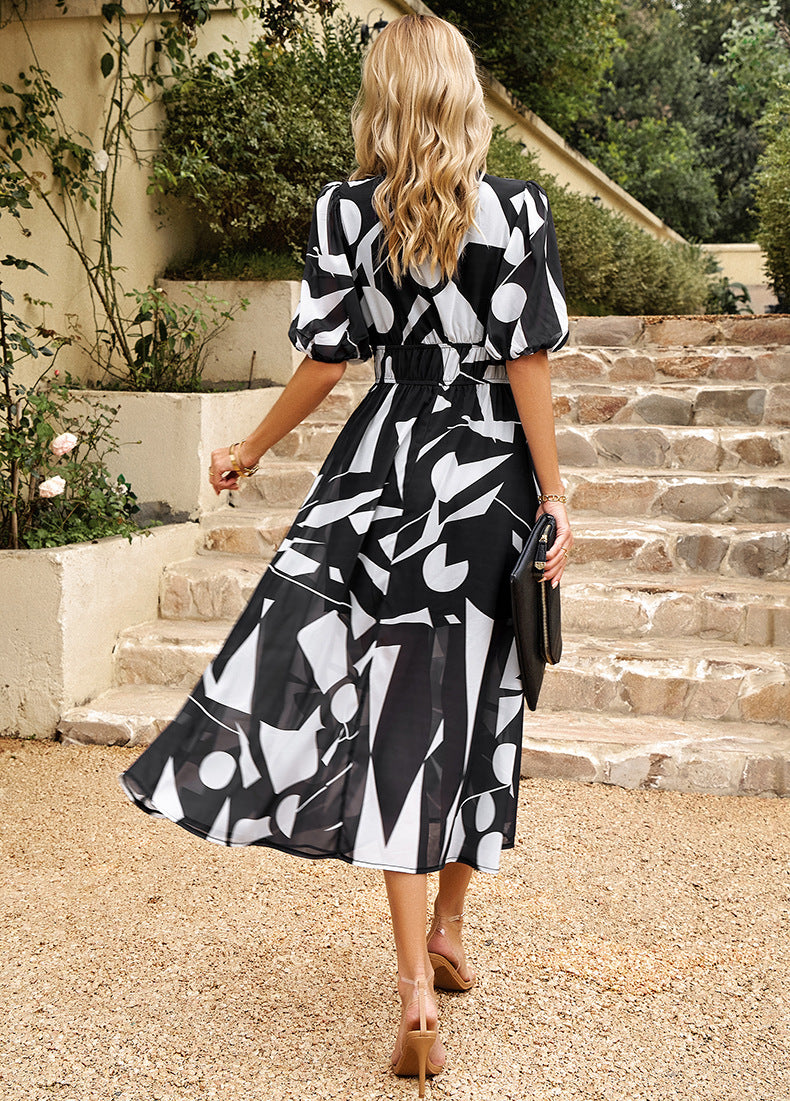 Back view of black-and-white abstract midi dress with V-neck and puff sleeves