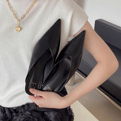 Black pointed-toe slip-on mules held in hand, low heel
