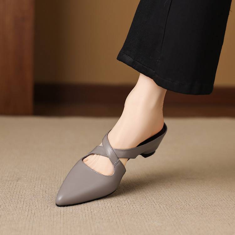 Gray pointed-toe mules with crisscross straps and low block heel on foot