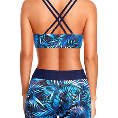 Blue tropical swim set shown from behind: strap-cross bikini top with leaf-print shorts