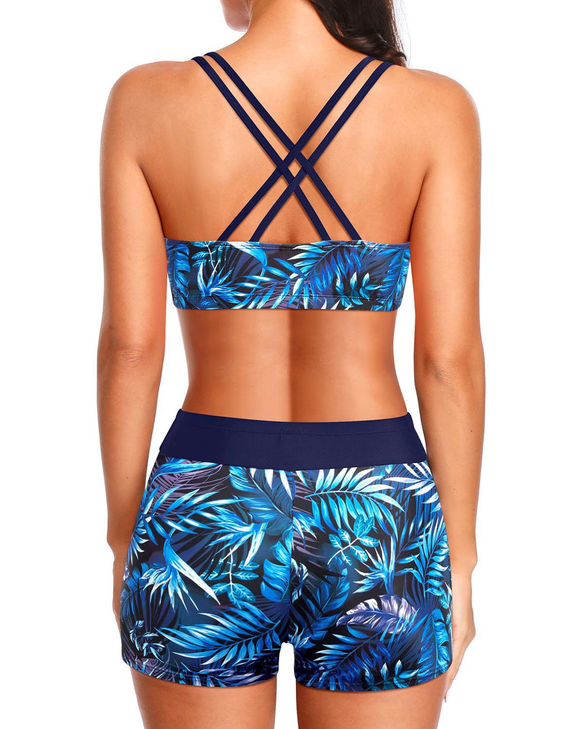 Blue tropical swim set shown from behind: strap-cross bikini top with leaf-print shorts