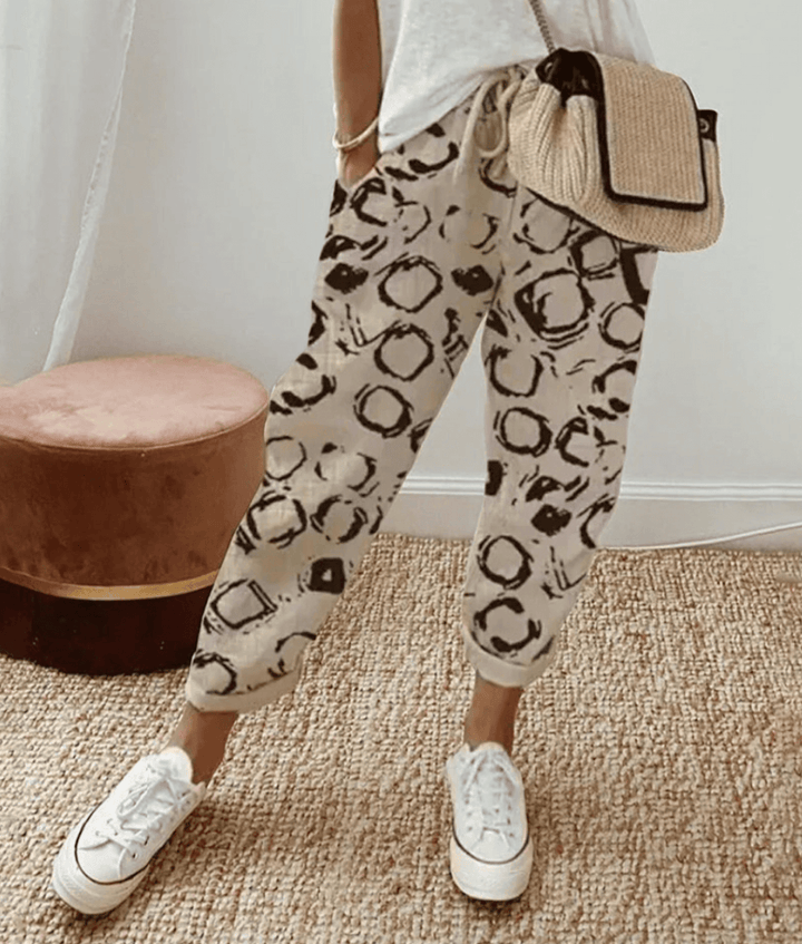 Beige cotton trousers with black circular print, elastic waist and cuffed hems