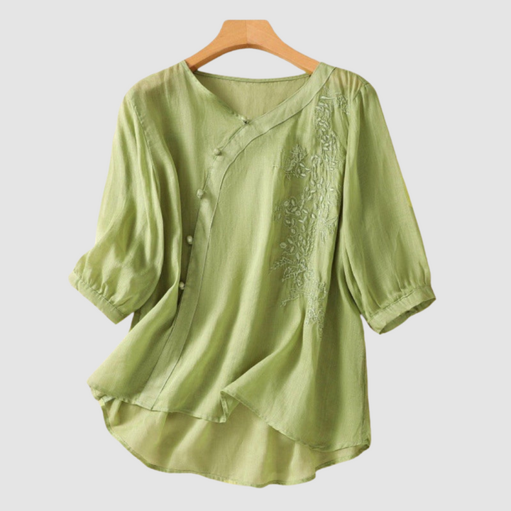 Light green breathable blouse with V-neck, button front, and embroidered side panel; short sleeves.