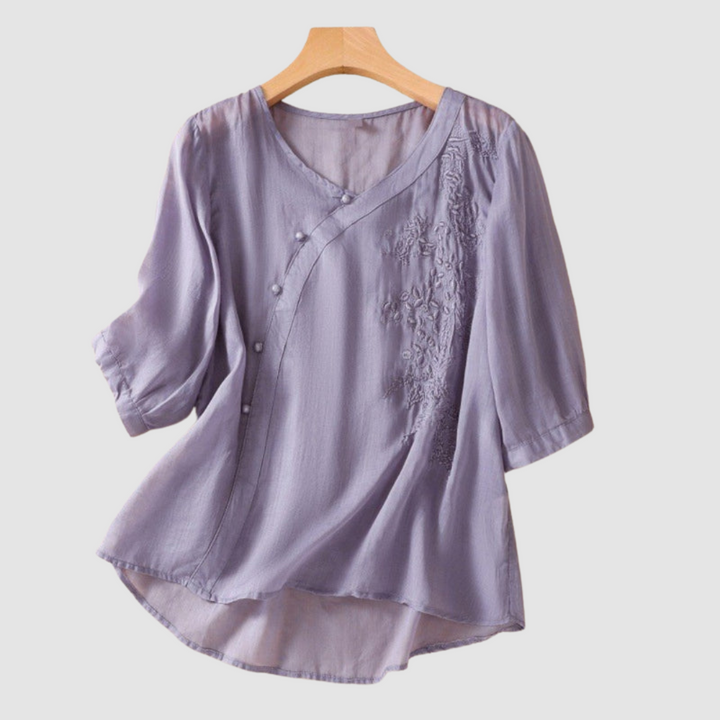 Lavender breathable blouse with V-neck, button placket, and embroidered chest detail; 3/4 sleeves.