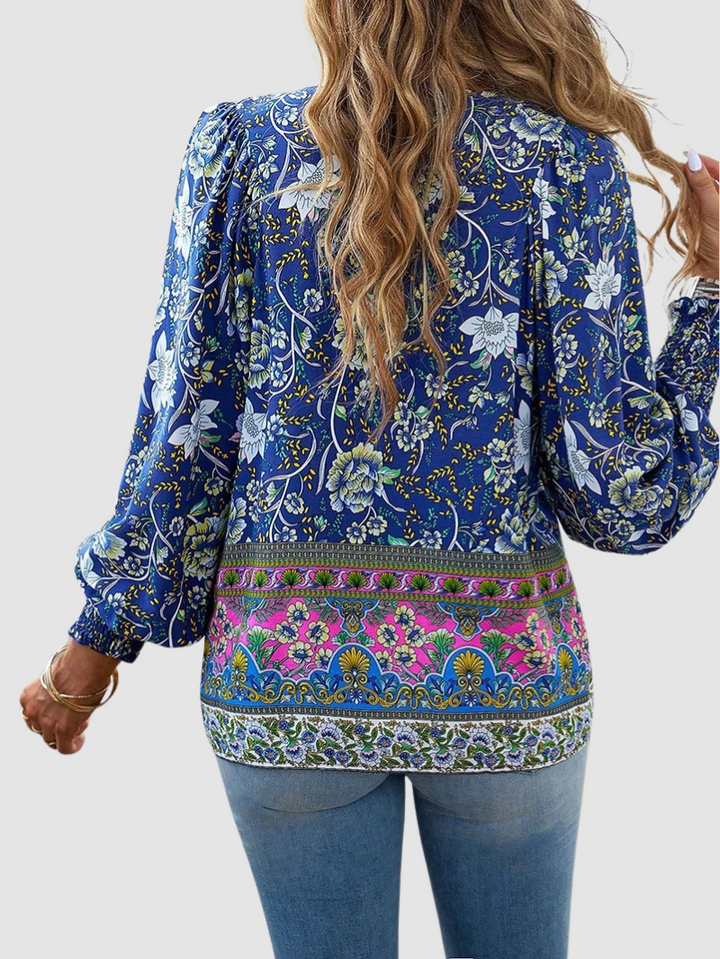 Back view of blue floral peasant blouse with long puff sleeves and decorative hem band