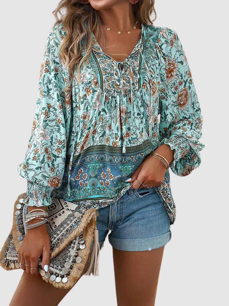 Front view teal floral peasant blouse with V-neck tie and long puff sleeves, patterned hem