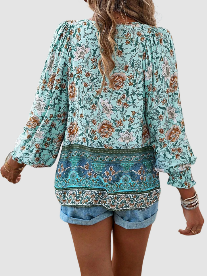 Back view teal floral peasant blouse with long puff sleeves and decorative hem band