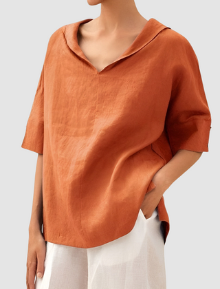 Orange short-sleeve blouse with V-neck and loose, draped fit.