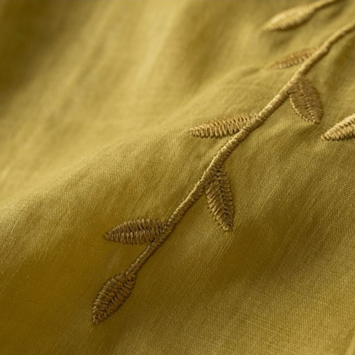 Close-up of leaf embroidery on olive green cotton-linen top fabric