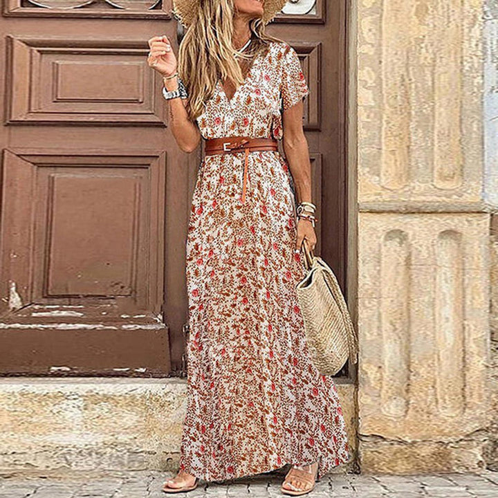 White bohemian maxi dress with red floral pattern, short sleeves, and waist belt