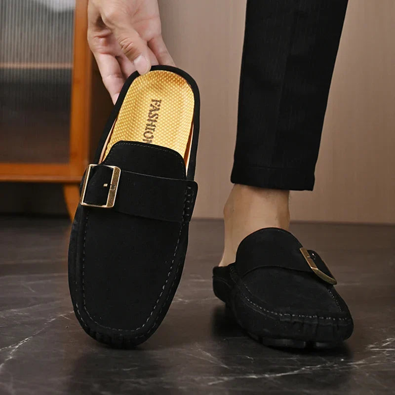 Black suede mules with square metal buckle strap and gold-toned insole, slip-on