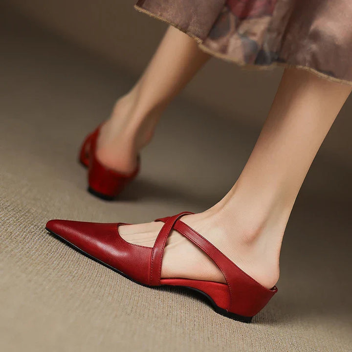 Red leather mules with pointed toe and slingback strap, low heel, angled view.