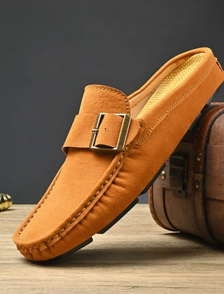 Tan suede mules with square buckle strap and moc-toe stitching
