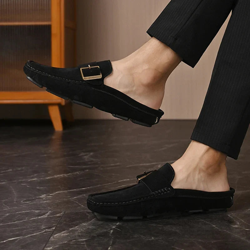 Black suede mules featuring a square buckle on the vamp and low sole