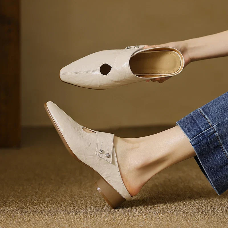 Beige leather mules with pointed toe, side cutout, and low heel