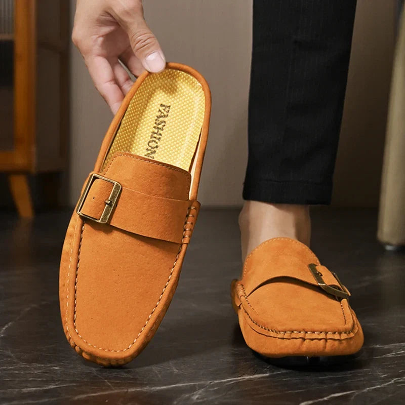 Tan suede mule with buckle strap, stitched trim, and textured insole