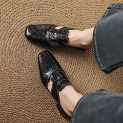 Black leather mule with buckle strap and squared toe, worn with denim