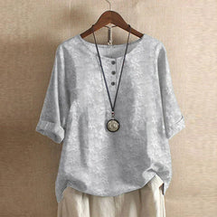Women’s light gray floral blouse with subtle blossom print, button-front, short sleeves.