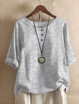 Women’s light gray floral blouse with subtle blossom print, button-front, short sleeves.