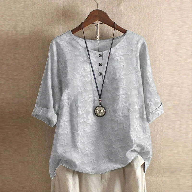 Women’s light gray floral blouse with subtle blossom print, button-front, short sleeves.