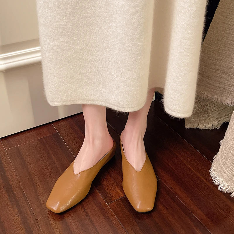 Brown pointed-toe mules with low flat heel and slip-on backless design.