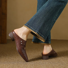 Brown leather mule with side cutout, stud detail, and low heel under jeans