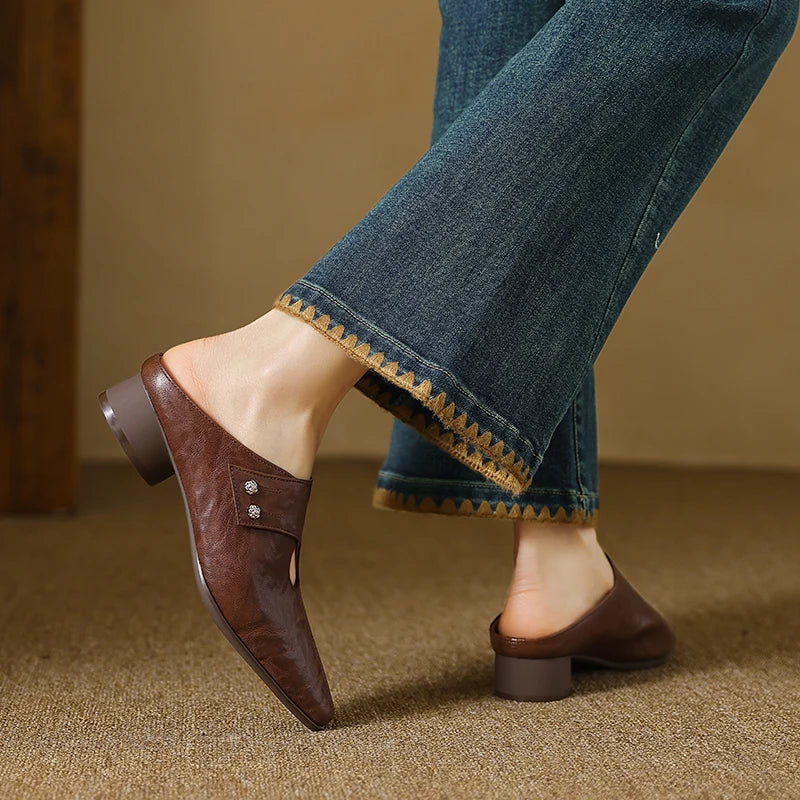 Brown leather mule with side cutout, stud detail, and low heel under jeans