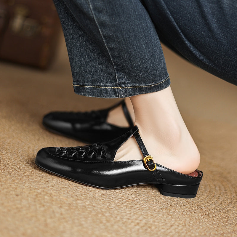 Black leather mule close-up with braided vamp and round gold strap buckle