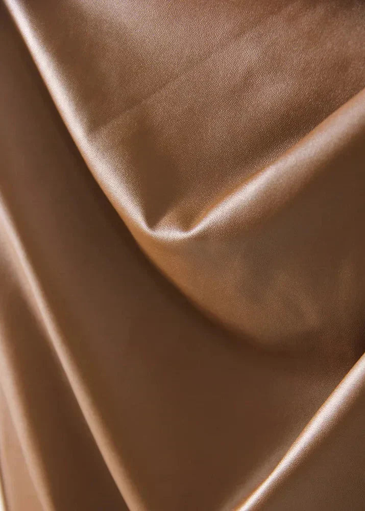 Close-up of bronze-brown leather with soft folds and smooth sheen