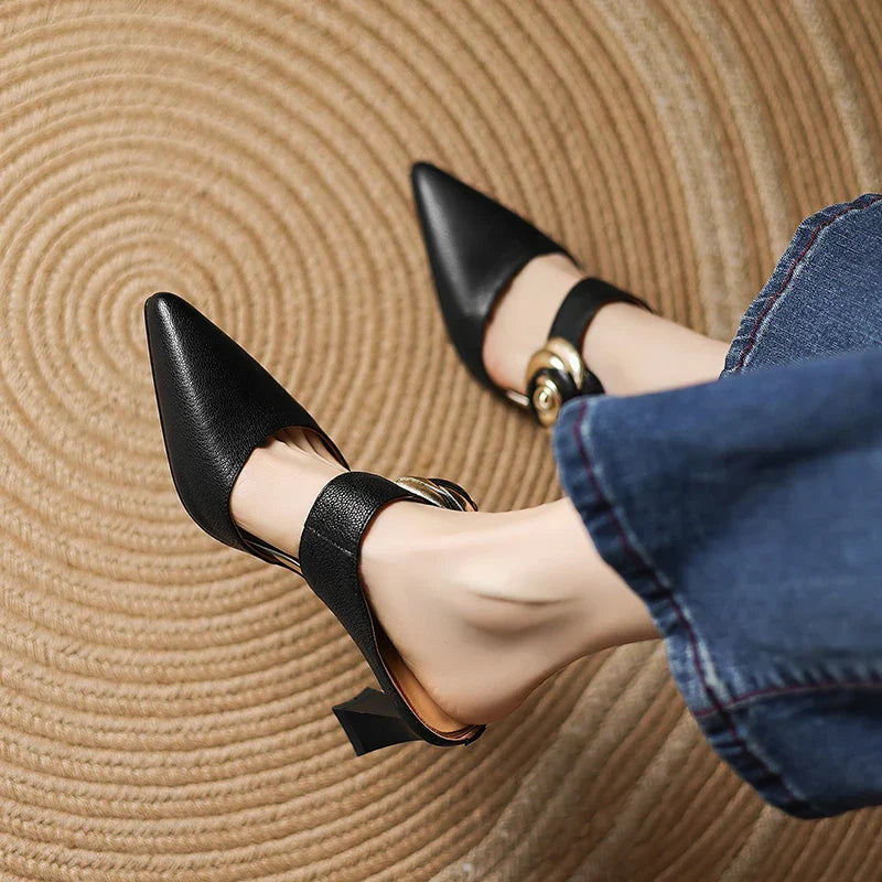 Black pointed-toe leather heels with ankle strap and rosette buckle on block heel