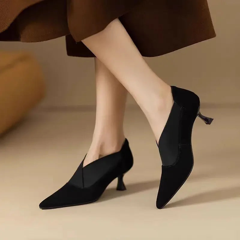 Black suede pointed-toe heels with mid heel, visible back seam