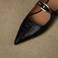 Close-up of black leather mule with pointed toe and silver buckle slingback strap