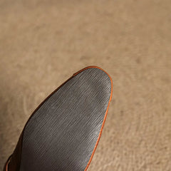 Brown leather mule outsole view with textured tread and orange trim edge