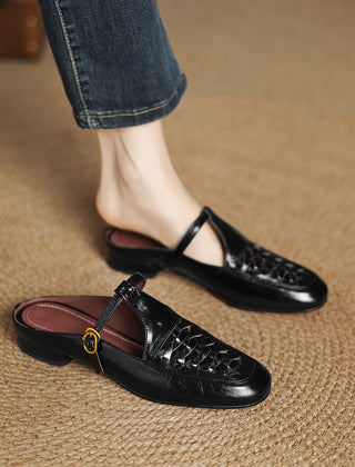 Black leather mule with braided vamp, sling strap, and round gold buckle