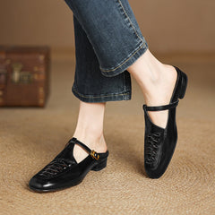 Black leather mules on foot with braided vamp and adjustable strap with gold buckle