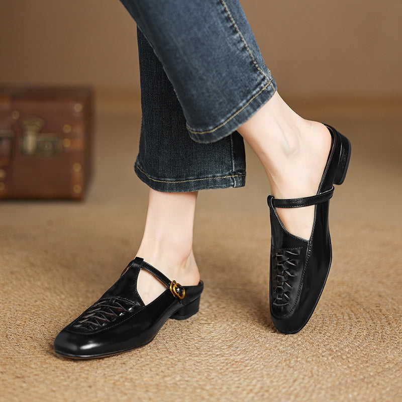Black leather mules on foot with braided vamp and adjustable strap with gold buckle
