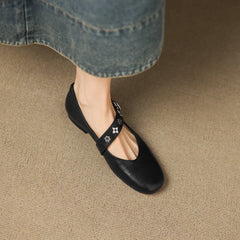 Black leather flats with star-pattern strap across the vamp and buckle