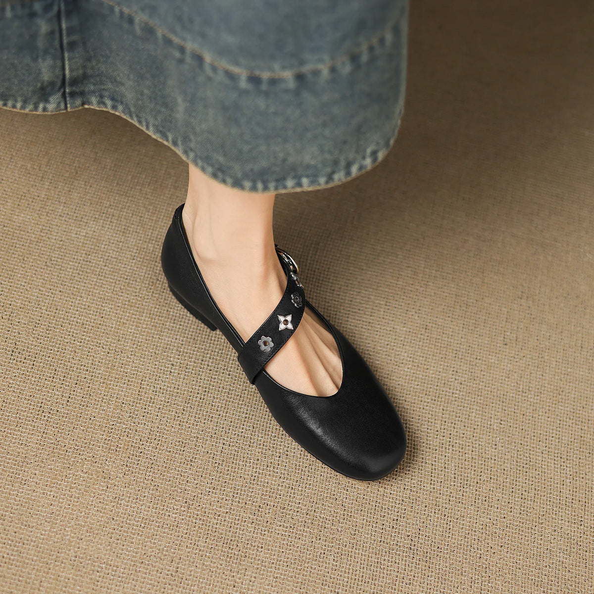 Black leather flats with star-pattern strap across the vamp and buckle